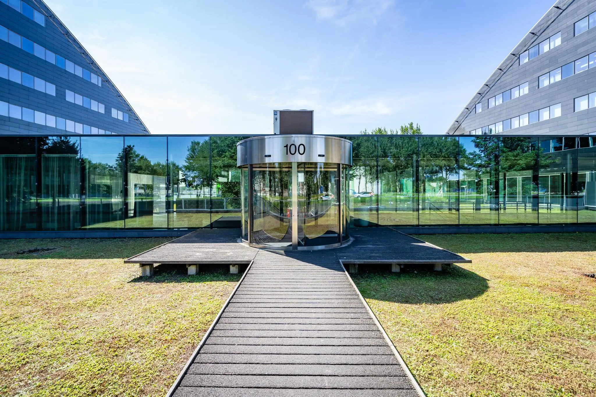 Glazen entree met draaideur van kantoorgebouw 100 aan de Rivium Promenade.